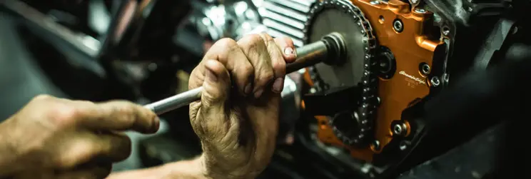 Técnico Harley-Davidson ajustando cadena de moto.